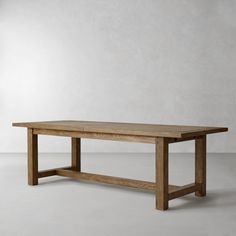 a large wooden table sitting on top of a white floor next to a gray wall