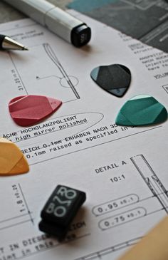 several different colored pieces of paper sitting on top of a piece of paper with a pen next to it