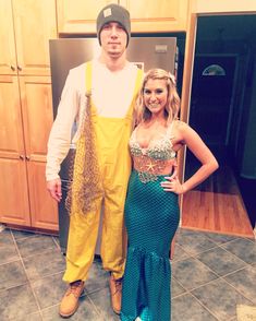 a man standing next to a woman in front of a refrigerator wearing yellow overalls