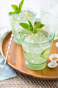 two glasses filled with ice and mint on a wooden tray