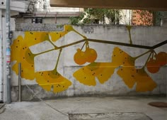 a painting on the side of a building with yellow flowers hanging from it's branches