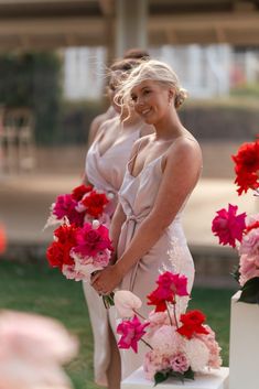 two women standing next to each other holding flowers