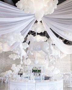 an elegant white wedding reception with balloons and chandeliers hanging from the ceiling above