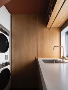 a washer and dryer in a kitchen with wood paneling on the walls