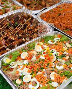 several trays filled with different types of food on top of green grass covered ground