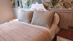 a bed with two pillows on top of it in front of a wallpapered headboard