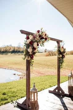 an outdoor ceremony setup with flowers and lanterns on the side of the aisle, overlooking a pond