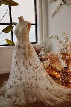 a wedding dress is displayed in front of a window with flowers and vases on the floor