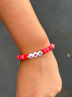 a close up of a person's arm wearing a red bracelet with white beads