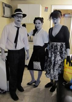 three people dressed up in costumes standing next to each other with luggage and bags on the floor