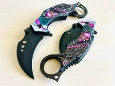 two knives with skulls on them sitting next to each other, one has a knife blade and the other has a black handle