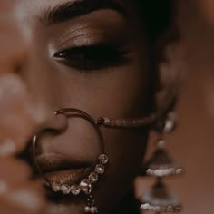 a close up of a woman's face with jewelry on her nose