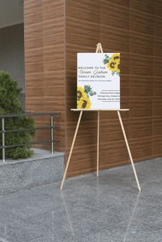 an easel stands in front of a building with a welcome sign