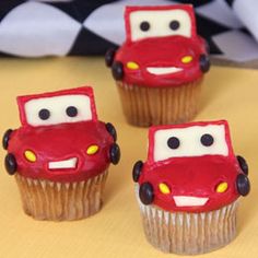 four cupcakes with cars on them sitting on a table