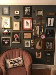 a chair sitting in front of a wall filled with pictures and framed photos on it