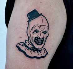 a person with a tattoo on their arm that has a drawing of a creepy clown