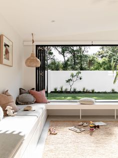 a living room filled with furniture next to a window covered in pillows and blankets on top of a rug