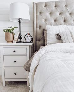 a bedroom with a bed, nightstand and clock on it's side table next to a lamp