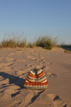 a knitted hat sitting on top of a sandy beach