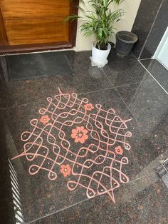 a black marble floor with pink and orange designs on it next to a potted plant