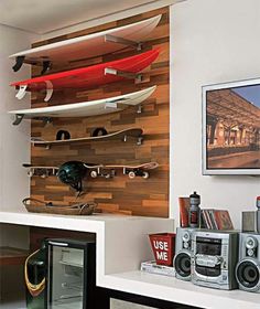 there are many surfboards mounted to the wall in this living room with speakers and stereos