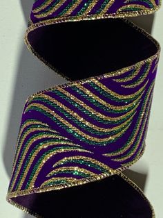 a purple and green striped ribbon with gold sequins