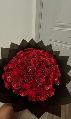 a bouquet of red roses sitting on top of a wooden table next to a door