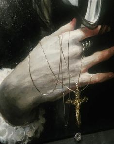 a person's hand holding a wine glass with a cross on it