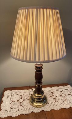 a lamp that is sitting on top of a wooden table next to a doily