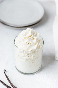 a glass jar filled with whipped cream on top of a white counter next to two plates