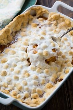 a casserole dish with a spoon in it on top of a wooden table