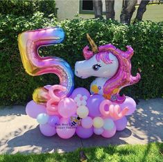 an inflatable unicorn balloon with the number five on it's head and balloons surrounding it