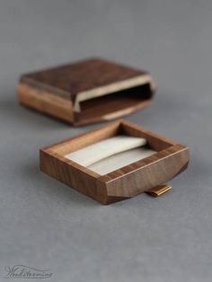 an empty wooden box sitting on top of a gray table next to a piece of paper