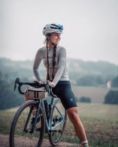 a woman is sitting on her bike in the countryside