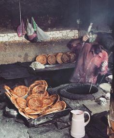 a woman cooking food in an outdoor kitchen