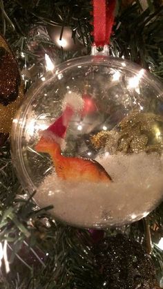 an ornament hanging from a christmas tree filled with snow and other holiday decorations