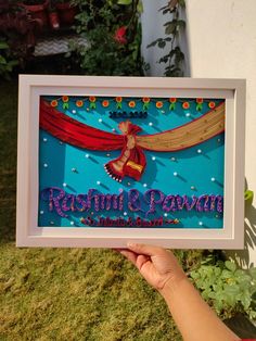 a person holding up a framed sign with the words rasshimi and pawan on it