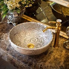 a bathroom sink sitting on top of a counter next to a vase filled with flowers