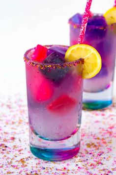 two glasses filled with different colored drinks and garnished with sprinkles