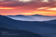 the sun is setting in the mountains with clouds and trees on it's sides