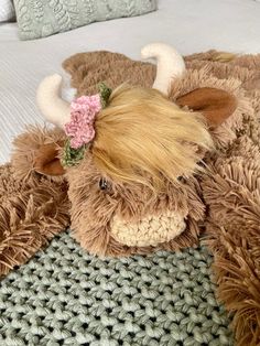 a stuffed animal with a flower in it's hair laying on top of a bed