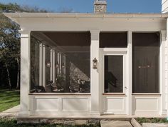 a screened porch with two chairs on the front and one sitting in the back yard