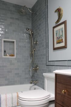 a white toilet sitting next to a bath tub in a bathroom under a framed mirror