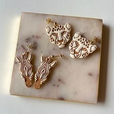 three different animal shaped earrings on a marble surface