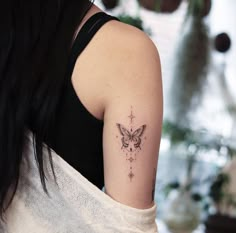 a woman with a butterfly tattoo on her left upper arm and cross behind her shoulder