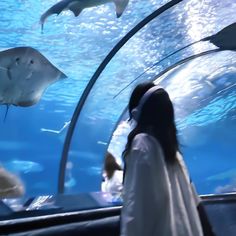 a woman is looking at fish in an aquarium while wearing a white robe and headphones