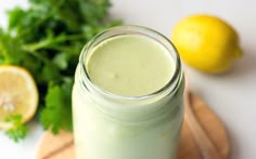 a green smoothie in a mason jar next to some lemons and parsley