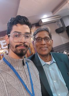 two men standing next to each other wearing glasses