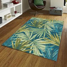 a blue rug with green leaves on it in a room next to a chair and bookshelf