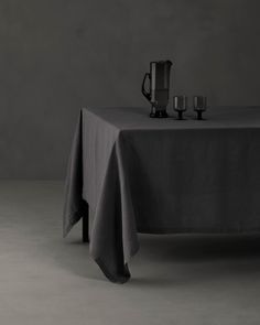 a table with a black cloth on it and two silver vases next to it